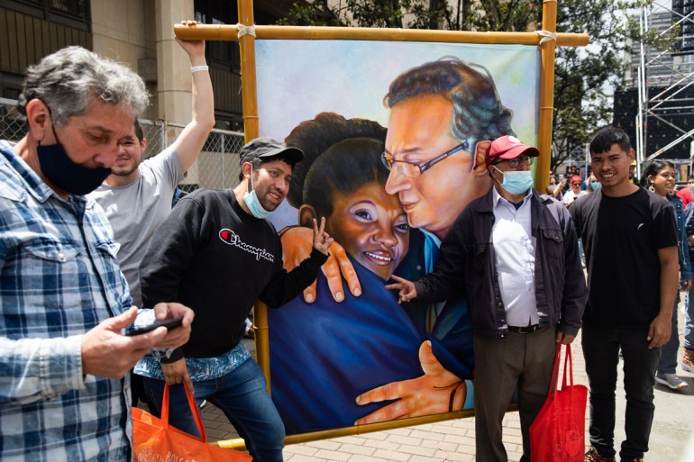 Supporters of President Gustavo Petro pose with a large-scale painting of the president with his vice president, Francia Marquez