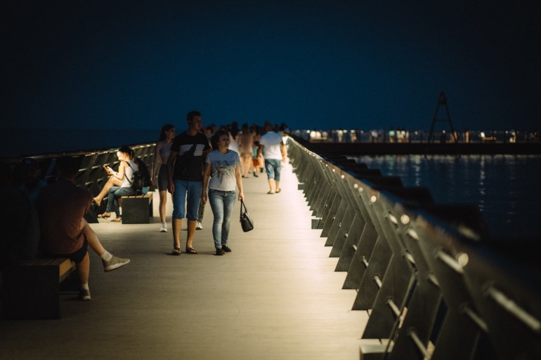 A photo of a pier at night with people walking along the pier.