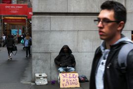 A homeless man sits near the New York Stock Exchange, where many of the world's wealthiest companies are listed.