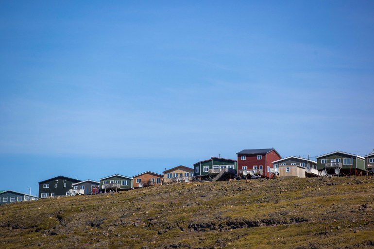 A view of the town of Iqaluit with a row of colourful houses on stilts.