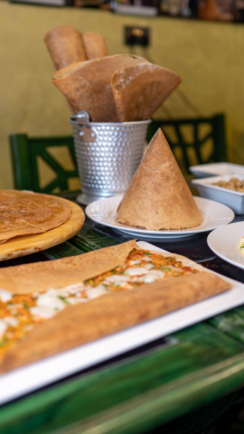 Photo of a green table full of breakfast dishes, regag breads with fillings and without, folded into fanciful shapes