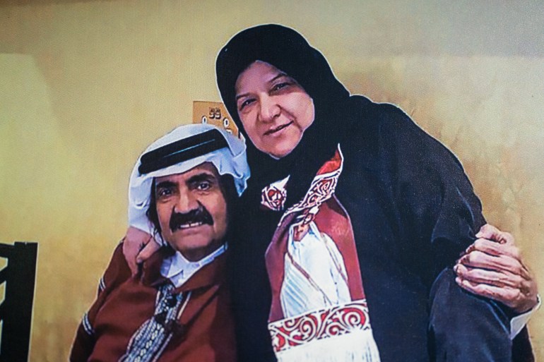 A photo of a photo of Shams standing with a seated Sheikh Hamad, her arm on his shoulder and his arm around her