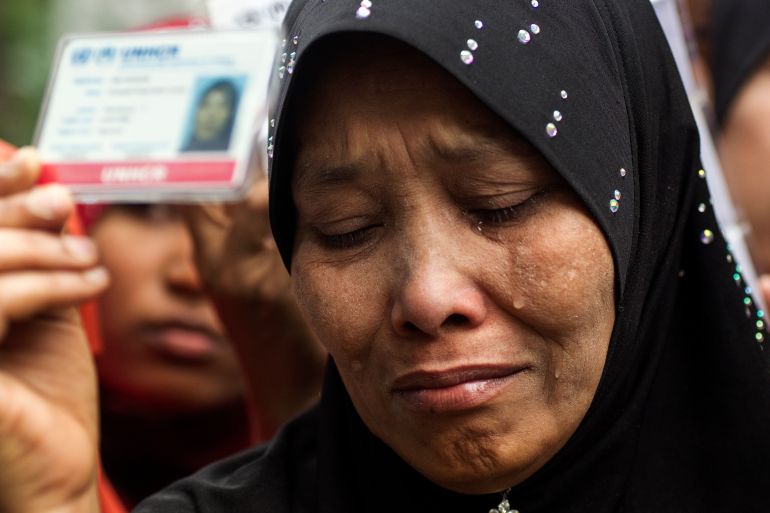 A Rohingya woman in a headscarf holds her the card given to her by UNHCR