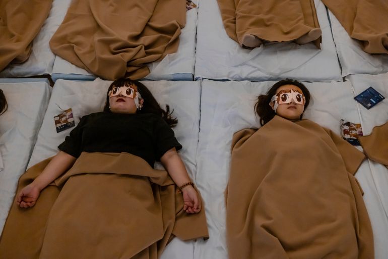Two women lie on the floor beneath blankets wearing eye masks in a Shanghai meditation studio