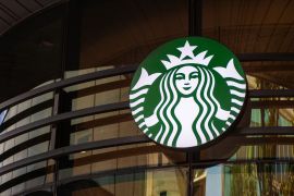 A logo hangs above the entrance to a Starbucks Corp. cafe in the Sandton area of Johannesburg, South Africa
