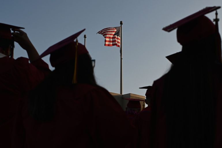 A US flag flies above a building as students earning degrees at Pasadena City College participate in the graduation ceremony