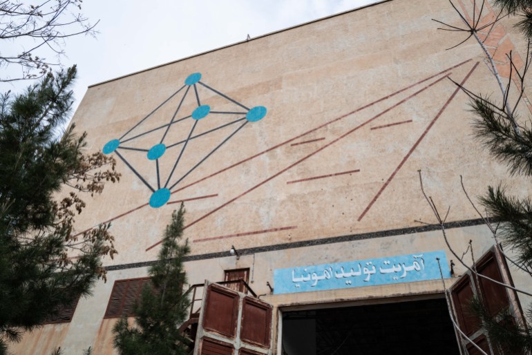 A photo of the outside wall of a building with an illustration of a box with lines and spots in it and some lines on the side of it.