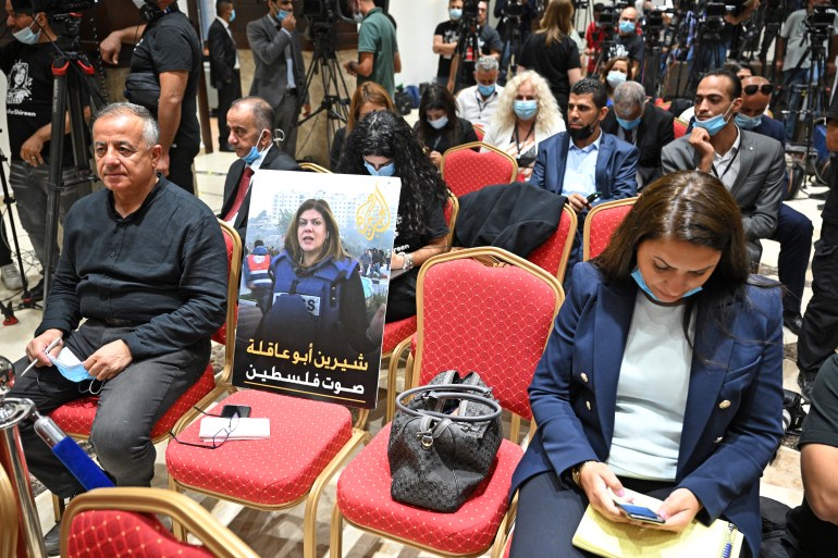 A photo of slain US-Palestinian Al Jazeera correspondent Shireen Abu Akleh, with a caption in Arabic reading "Shireen Abu Akleh, the voice of Palestine", is seen amongst reporters ahead of a joint press conference between the US and Palestinian presidents on July 15, 2022.