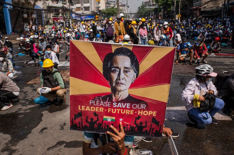 Protesters in Myanmar hold a banner of Aung San Suu Kyi saying 'Please save our leader'