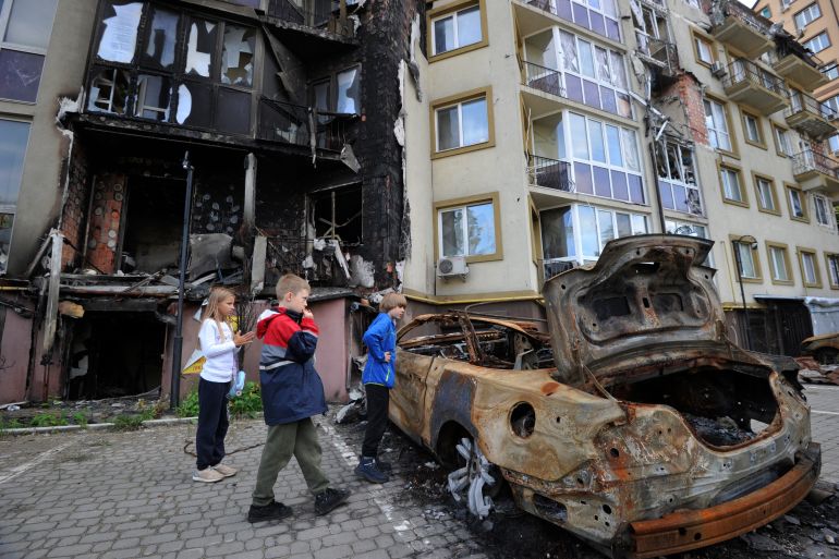 Children look at a burned car near a damaged residential building in the city of Irpin on September 11, 2022, amid the Russian invasion of Ukraine. - Ukraine said on Sptember 11, 2022, that its forces were pushing back Russia's military from strategic holdouts in the east of the country after Moscow announced a retreat from Kyiv's sweeping counter-offensive. (Photo by Sergei CHUZAVKOV / AFP) / The erroneous mention[s] appearing in the metadata of this photo by Sergei CHUZAVKOV has been modified in AFP systems in the following manner: [Irpin] instead of [Izium, Kramatorsk]. Please immediately remove the erroneous mention[s] from all your online services and delete it (them) from your servers. If you have been authorized by AFP to distribute it (them) to third parties, please ensure that the same actions are carried out by them. Failure to promptly comply with these instructions will entail liability on your part for any continued or post notification usage. Therefore we thank you very much for all your attention and prompt action. We are sorry for the inconvenience this notification may cause and remain at your disposal for any further information you may require.