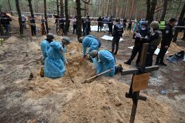 Forensic technicians dig a grave in a forest on the outskirts of Izyum, eastern Ukraine