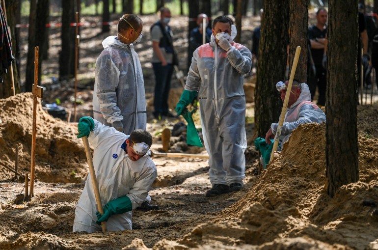 Forensic technicians dig at the site of a mass grave in a forest on the outskirts of Izyum