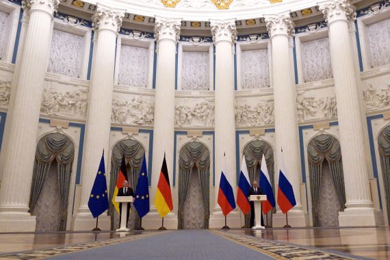 German Chancellor Olaf Scholz and Russian President Vladimir Putin speaking from lecterns during a press conference..