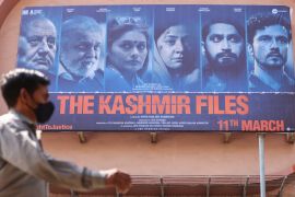 A man walks past a poster of Bollywood movie "The Kashmir Files" outside a cinema in Mumbai, India, March 16, 2022.