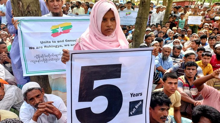 A Rohingya girl in a pink headscarf holds a sign with the number '5' as Rohingya gather to mark five years since they were driven out of Myanmar
