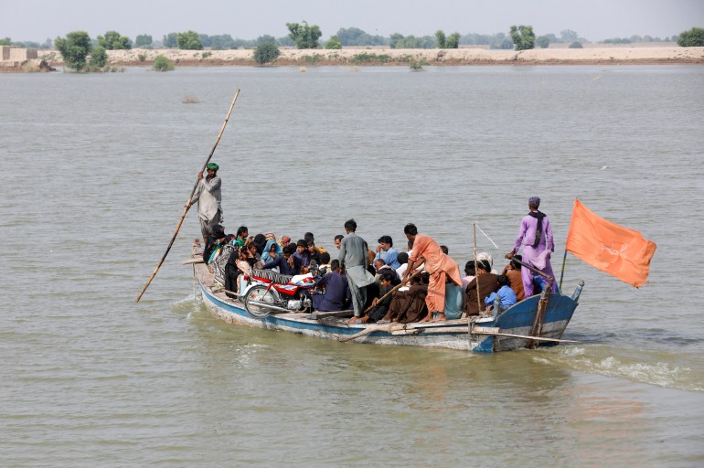 Residents travel in a boat through flood water while heading to their villages, following rains and floods during the monsoon season in Sehwan, Pakistan September 13, 2022.