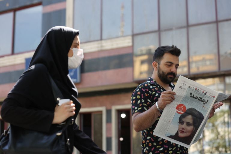 A man views a newspaper with a cover picture of Mahsa Amini, a woman who died after being arrested by the Islamic republic's "morality police"