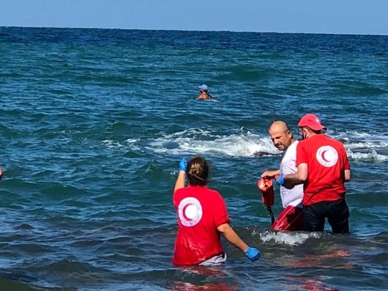 Members of Syrian Red Crescent work at a shoreline following the shipwreck