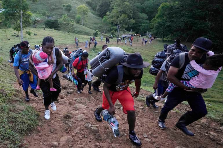 Refugees and migrants, who are mostly Haitians, climb up a hill on their way to crossing the Darien Gap from Colombia into Panama.