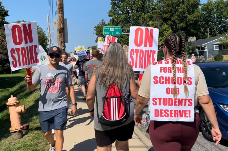 union members carry signs that say on strike outside a high school in Colombus, Ohio