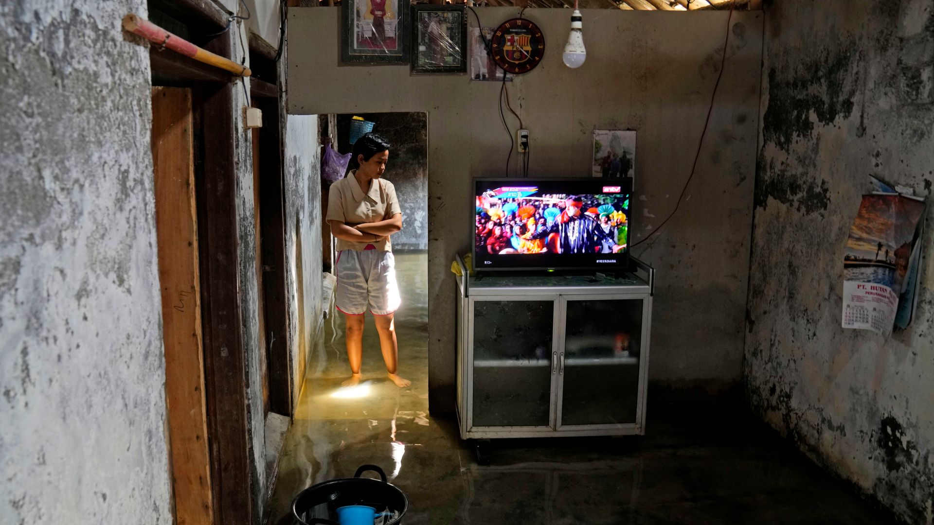 Dwi Ulfani stands inside her flooded home