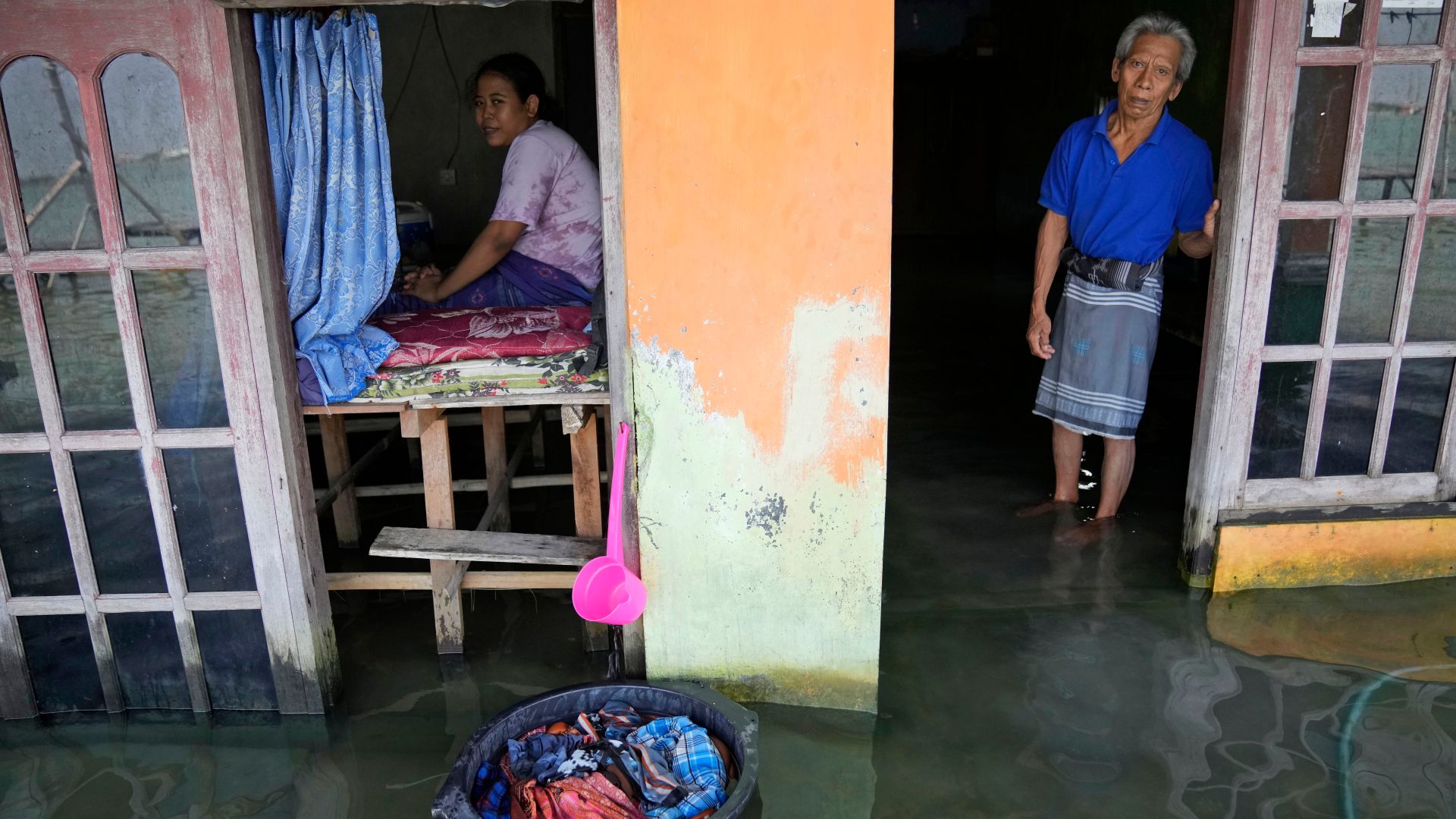 Sudarto stands at the door of his flooded home