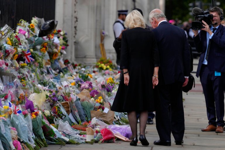 King Charles III and Camilla, the Queen Consort, looks at flowers and read messages left by mourners.