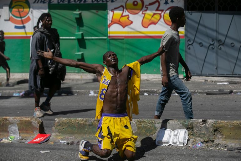 A protester kneels in Haiti