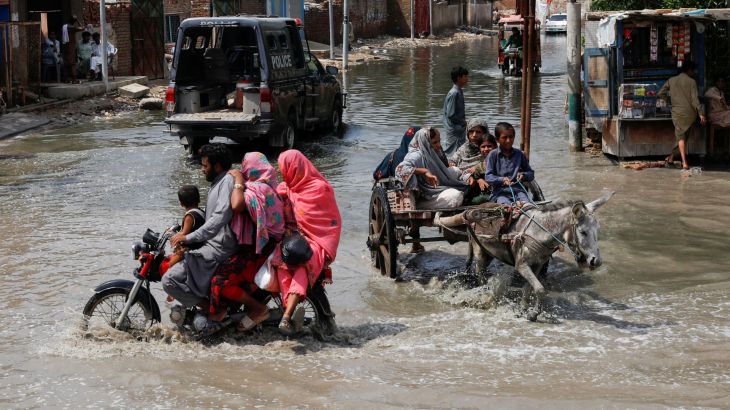 Commuters travel through flood waters in Pakistan