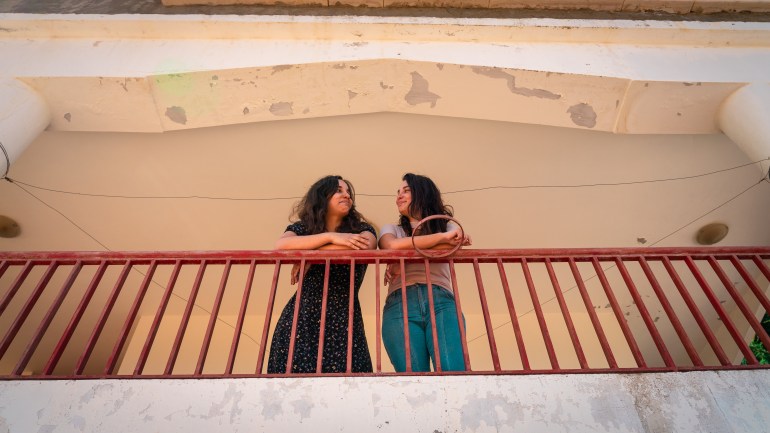 Sali Hafiz (r) and her sister Ekraam standing on a balcony and looking at each other