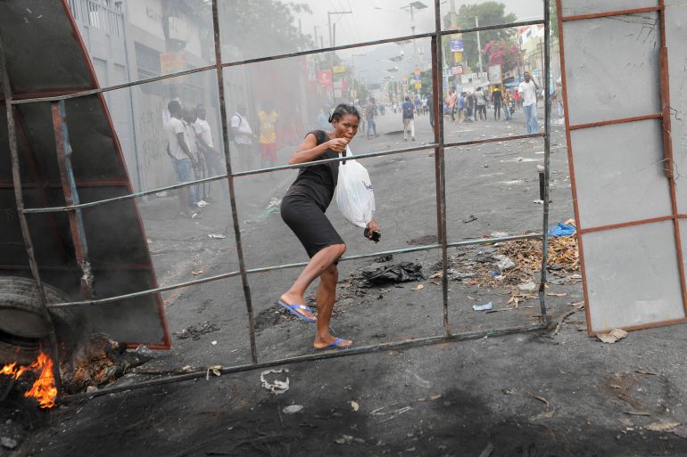A woman crosses a barricade set up by demonstrators in Haiti's capital of Port-Au-Prince as protests rage in Haiti.