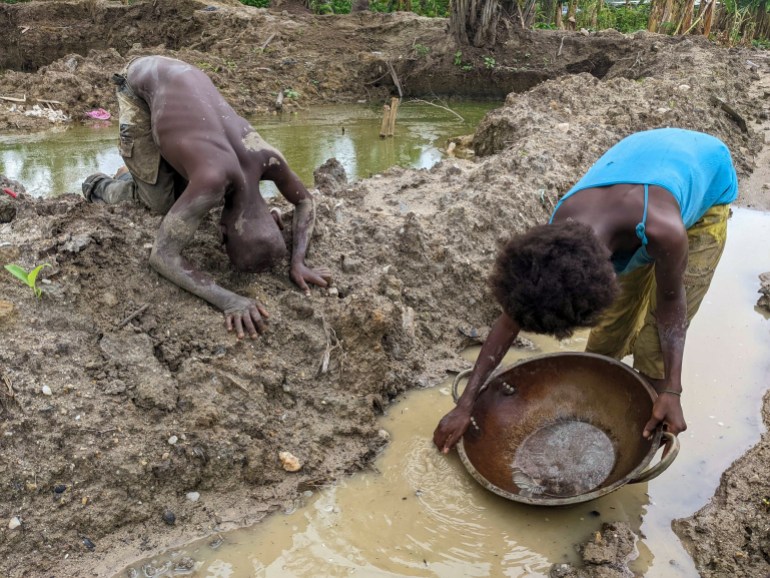 A young boy and young girl look for gold particles in a small mining site in Iperindo, Osun state. [Eromo Egbejule/Al Jazeera]