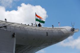 A photo of Indian Navy officers standing on the flight deck of the aircraft carrier INS Vikrant.