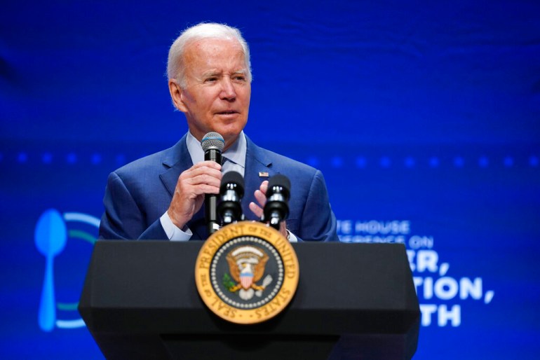 President Joe Biden speaks at a lectern during a conference.