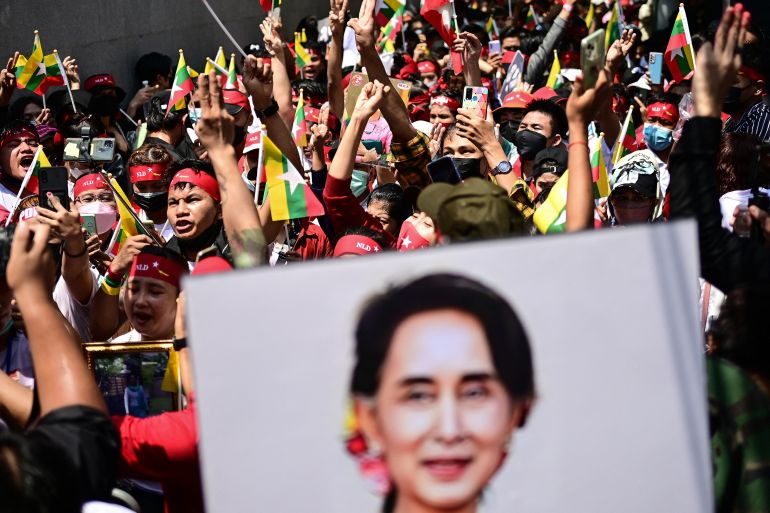 Protesters show the three-finger salute and hold photos of jailed Myanmar leader Aung San Suu Kyi during a demonstration against Myanmar military government in July 2022