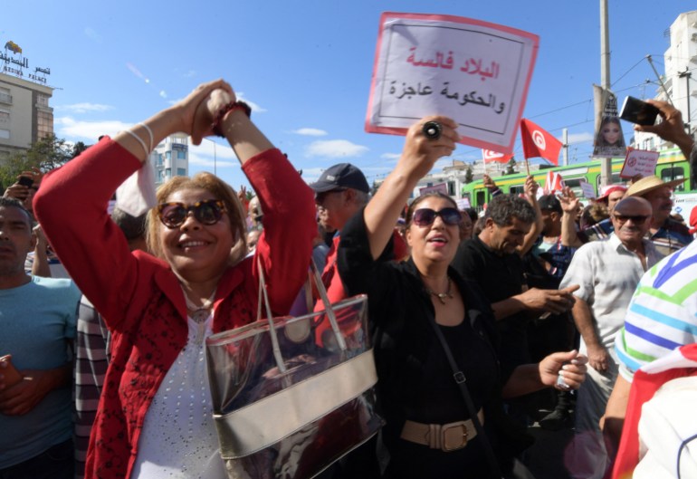A supporters of the Tunisian Free Destourian Party raises a placard that reads in Arabic : "the country is bankrupt and the government is disabled", during a demonstration against President Kais Saied in the capital Tunis, on October 15, 2022. (Photo by FETHI BELAID / AFP)