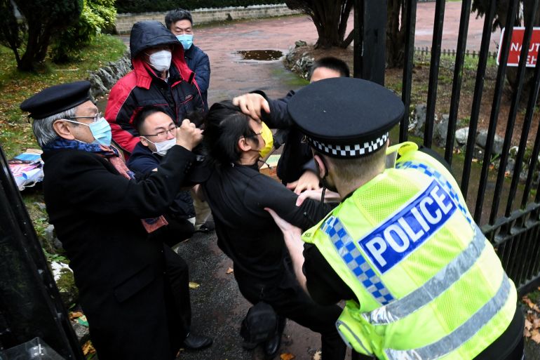 A scuffle between a Hong Kong pro-democracy protester (centre) and Chinese consulate staff in face masks, at the gates of the Chinese consulate in Manchester as a British police officer in uniform and a hi-vis vest attempts to intervene.