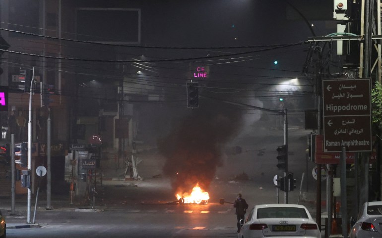 Protesters burn tires in the streets of Nablus during clashes with Israeli forces early on October 25, 2022 [Jaafar Ashtiyeh/AFP]