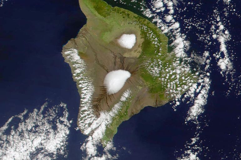 NASA satellite images show two peaks of snow on the tops of the Mauna Kea (upper) and Mauna Loa (lower) volcanoes with clouds above