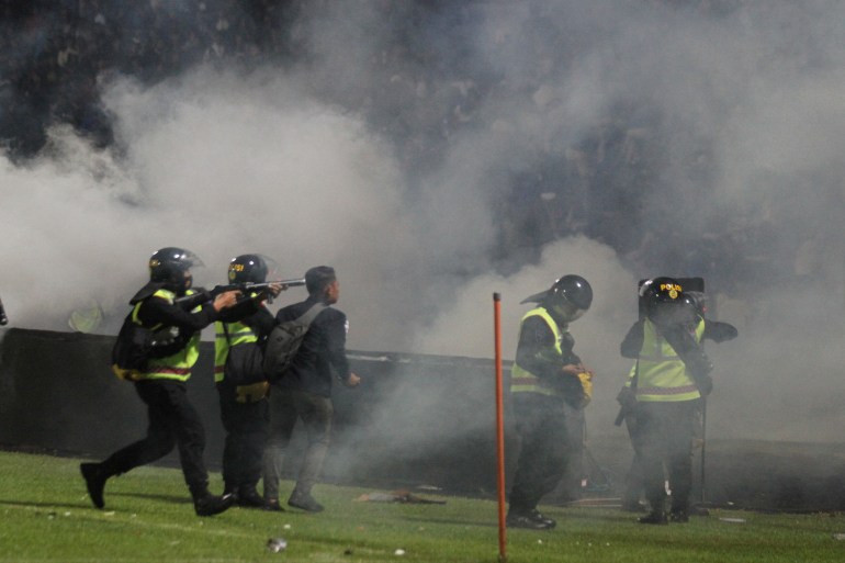 Indonesia police fire off clouds of tear gas as they stand on the pitch after Arema vs Persebaya at Kanjuruhan Stadium