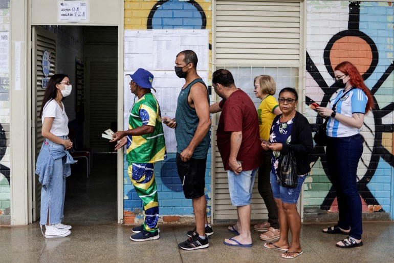 A supporter of Brazil's president and candidate for re-election Jair Bolsonaro, Mauro Pinto waits in line to cast his vote at a polling station, in Brasilia, Brazil.