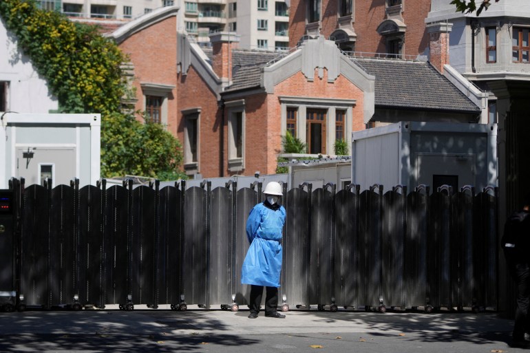 A security guard in a protective overall stands guard at a sealed off residential area in Shanghai