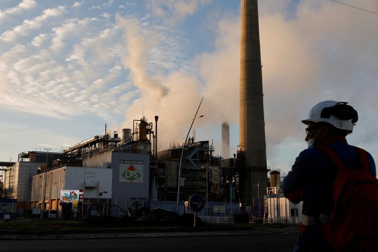 A worker stands in front of the ExxonMobil oil refinery in Port-Jerome-sur-Seine, France