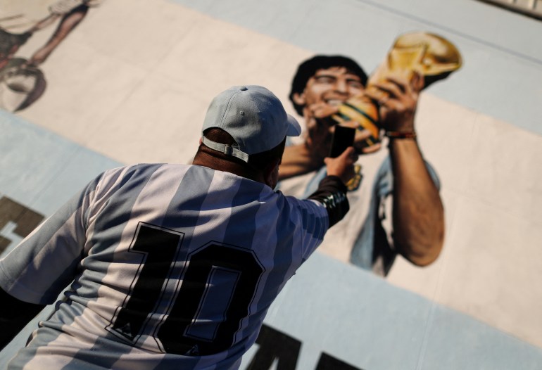 A fan of Argentine soccer superstar Diego Armado Maradona takes a picture of a mural as he celebrates the idol's 35th anniversary of the "goal of the century", against England during the 1986 World Cup played in Mexico, in Buenos Aires, Argentina 