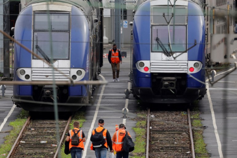 Workers walk past TER regional trains at the SNCF depot of Hellemmes-Lille on the eve of a nationwide day of strike and protests for wages and against requisitions at refineries in France