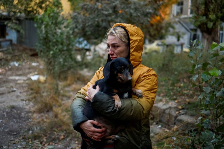 A woman carries a dog at a site of a residential building heavily damaged by a Russian missile strike, amid their attack on the country, in Mykolaiv, Ukraine October 18, 2022. REUTERS/Valentyn Ogirenko TPX IMAGES OF THE DAY