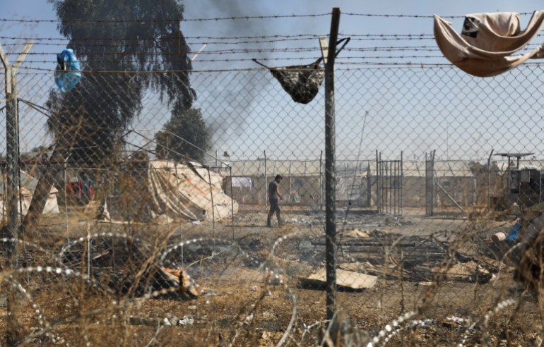 A migrant walks next to burned tents in Pournara refugee camp during clashes in Kokkinotrimithia on the outskirts of Nicosia