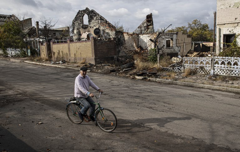 KHERSON, UKRAINE - OCTOBER 24: A man rides his bike near damaged buildings at Velyka Oleksandrivka town, located in the Kherson region where the control was retaken by the Ukrainian forces, after Ukraine's counterattack against Russian forces in Kherson Oblast, Ukraine on October 24, 2022. Ukrainian forces retook 90 settlements in Kherson as the counter offensive launched on Aug. 29 continues, according to information provided by officials. ( Metin Aktaş - Anadolu Agency )