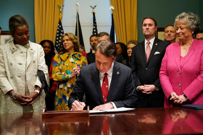 Virginia Gov. Glenn Youngkin, center, signs executive orders in the Governors conference room as Lt. Gov. Winsome Earle-Sears, left, Suzanne Youngkin, second from left, Attorney General Jason Miyares, second from right, and Secretary of the Commonwealth, Kay Cole James, right, look on at the Capitol, Jan. 15, 2022, in Richmond, Va. Virginia's Department of Education is conducting a review designed to root out critical race theory in schools. The review is the first thing Gov. Youngkin ordered after his inauguration and is expected to conclude later this month. Education officials have been reluctant to discuss what they've found thus far. While critics of the governor say critical race theory is a nonissue, others say there is ample evidence that the concepts have been embraced by administrators. (AP Photo/Steve Helber)