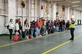Ukrainian refugees line up as they arrive to get accommodations on the ferry Isabelle in Tallinn, Estonia